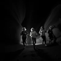 Low-angle B&W photo of joyful older adult runners with headlamps in a rain-misted desert canyon at night