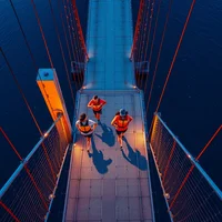 Aerial pointillist painting of four adult joggers in hydration vests racing across a suspension bridge at blue-hour dusk.