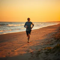 Runner jogging on beach at sunset with golden sky and ocean waves in background