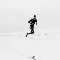 Elite runner in racing gear crossing snowy hills during blizzard, shot in dramatic black and white