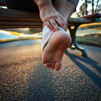 Runner on a bench at sunrise gripping a bare heel, the discomfort that makes a night splint hard to stick with