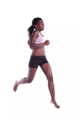 Woman in pink sports bra and black shorts running barefoot in profile against a white background